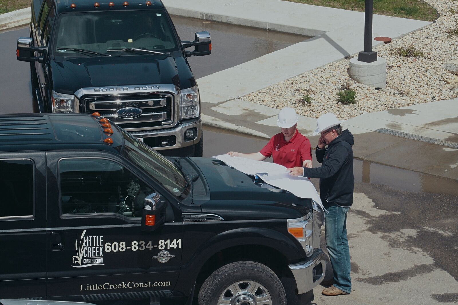Alex and Mike Filkouski reviewing building plans on the hood of a Little Creek truck